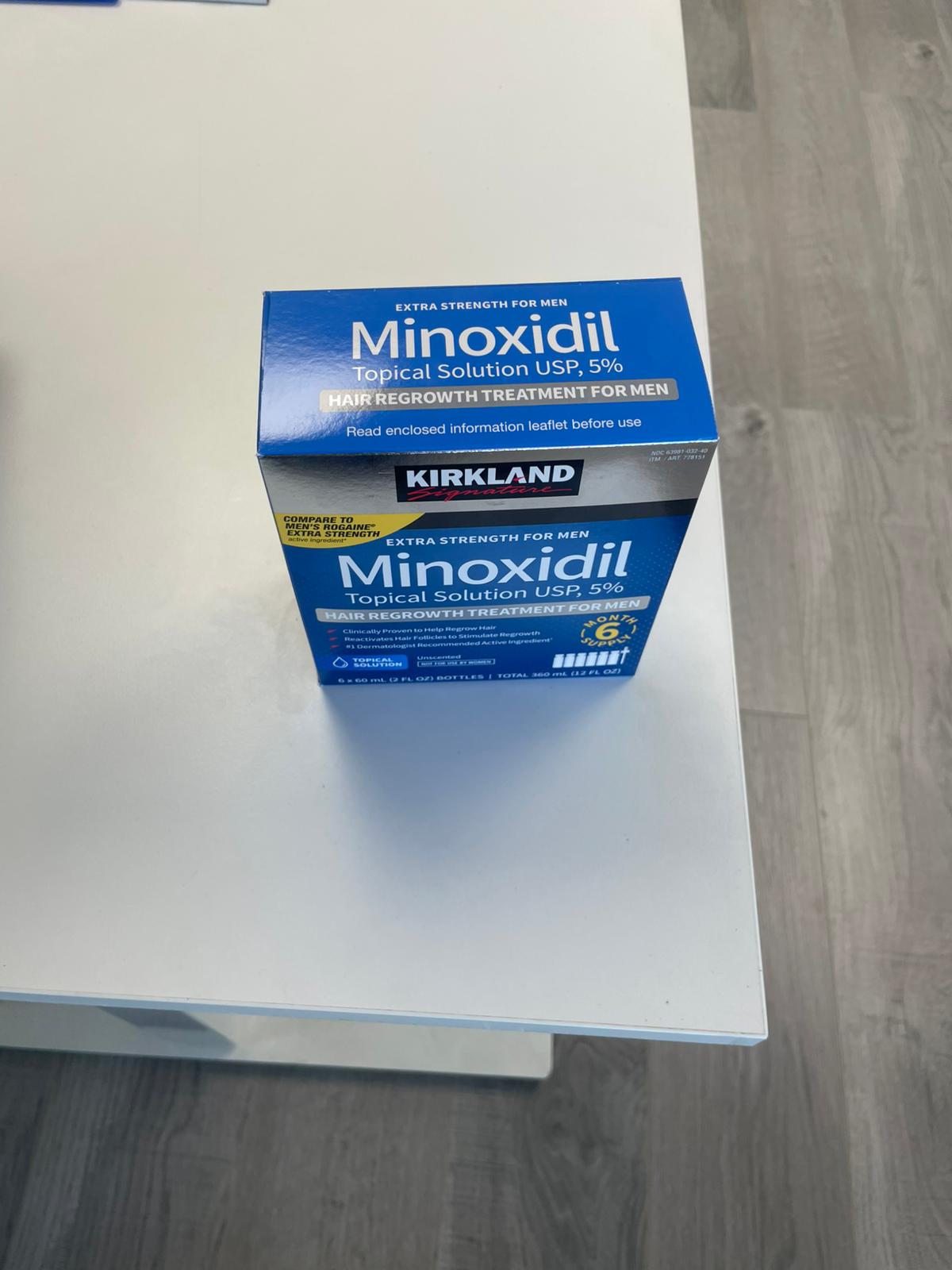 Kirkland Minoxidil box on a white surface with a wooden floor background